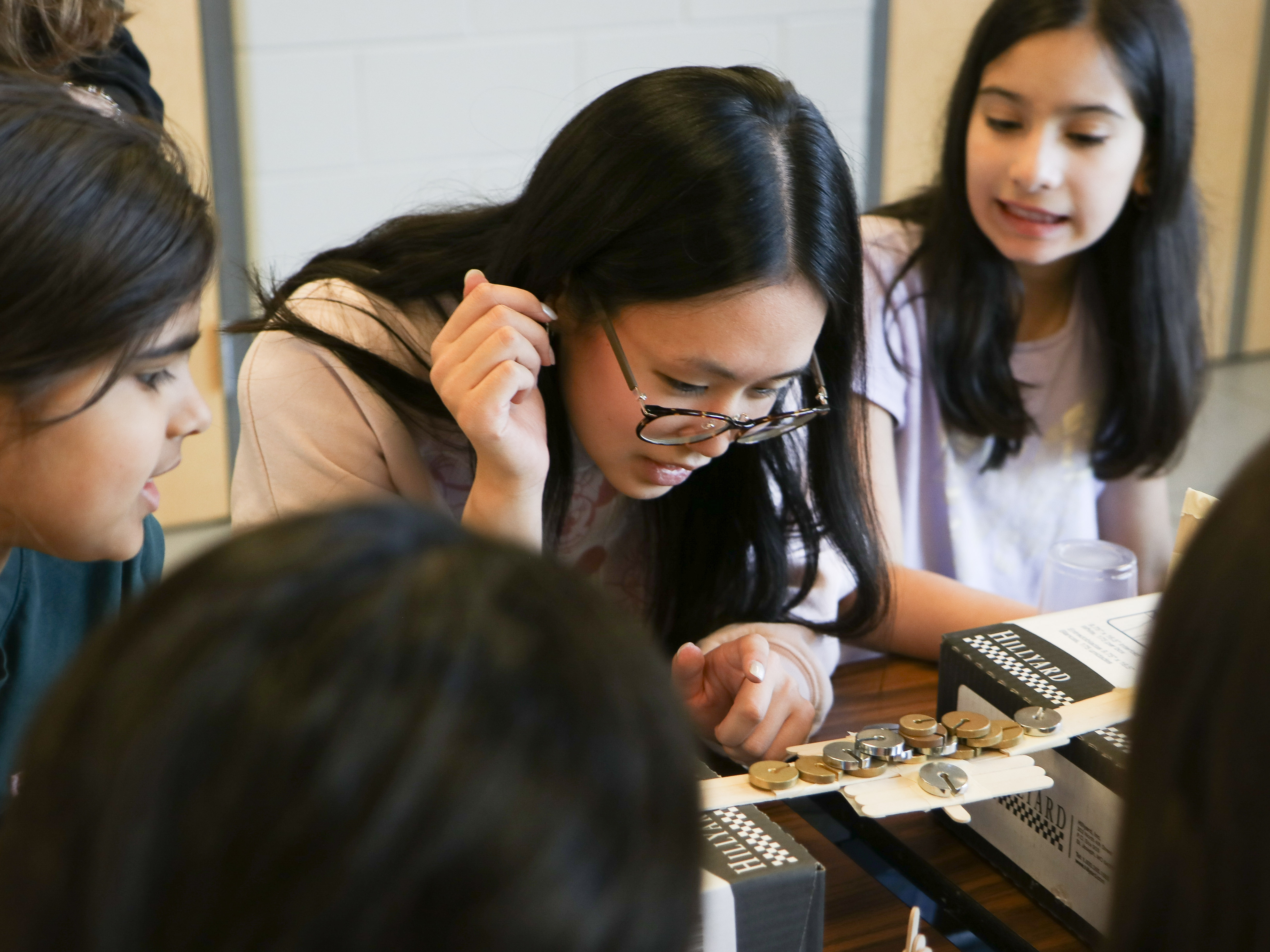 Students load-testing a popsicle-stick bridge together