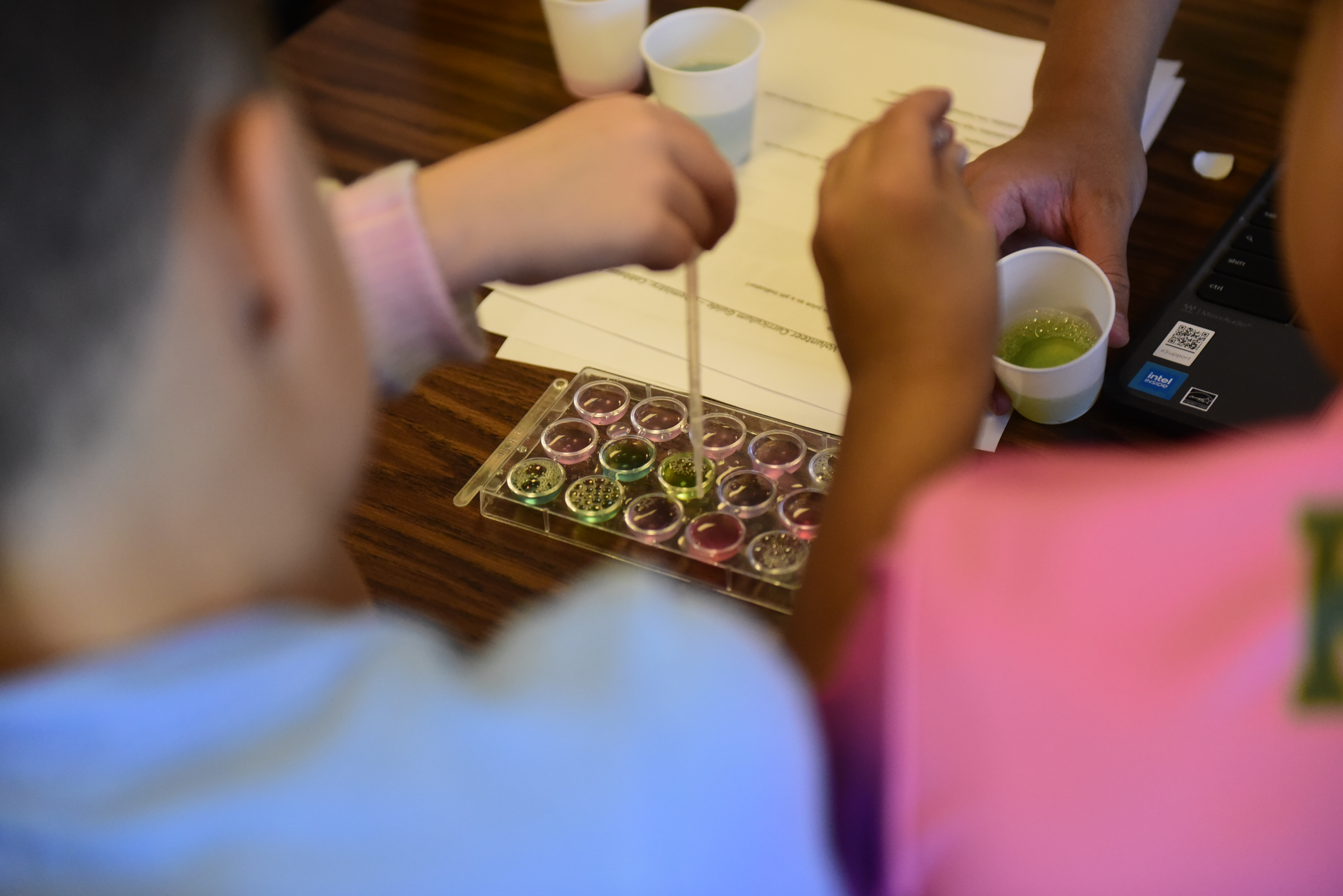 Students pipetting colorful solutions during a chemistry workshop
